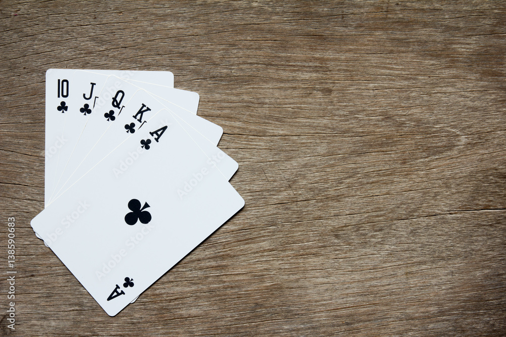 Five card of black club royal straight flush on wooden background