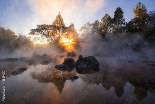 The hot spring with a 73 degree Celsius water spring over rocky terrain. heat from the hot spring providing a misty and picturesque scene which is particular beautiful in the morning. photo