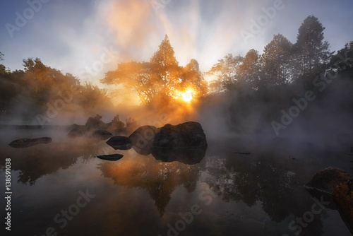 The hot spring with a 73 degree Celsius water spring over rocky terrain. heat from the hot spring providing a misty and picturesque scene which is particular beautiful in the morning. photo
