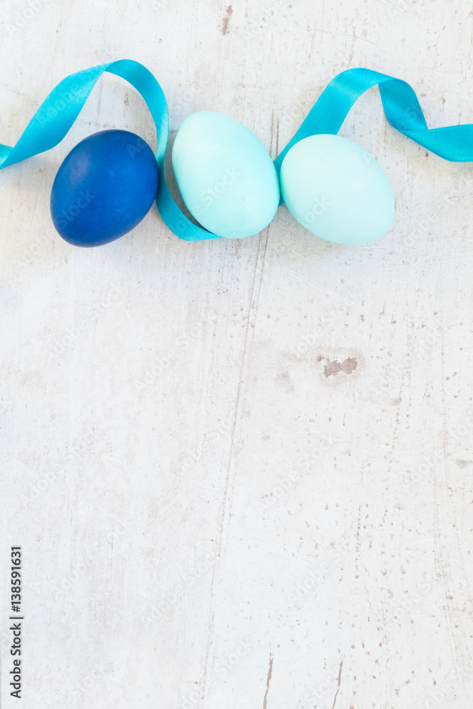 Blue easter eggs and ribbon, white aged wooden tabletop with copy space Blue easter eggs and ribbon, white aged wooden tabletop with copy space