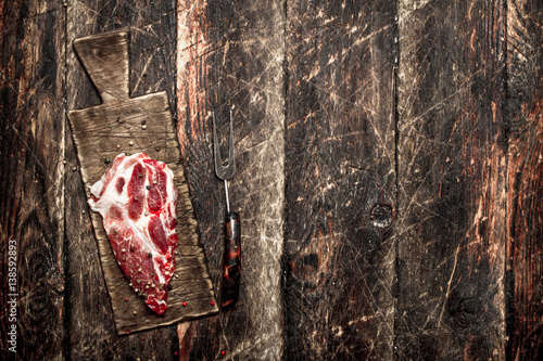 Raw meat background. A piece of raw steak on cutting Board . On wooden background.