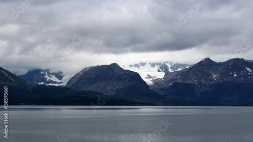 schwarze Schnee bedeckte und Wolken verhangene Berge am Lyngenfjord, Troms, Norwegen