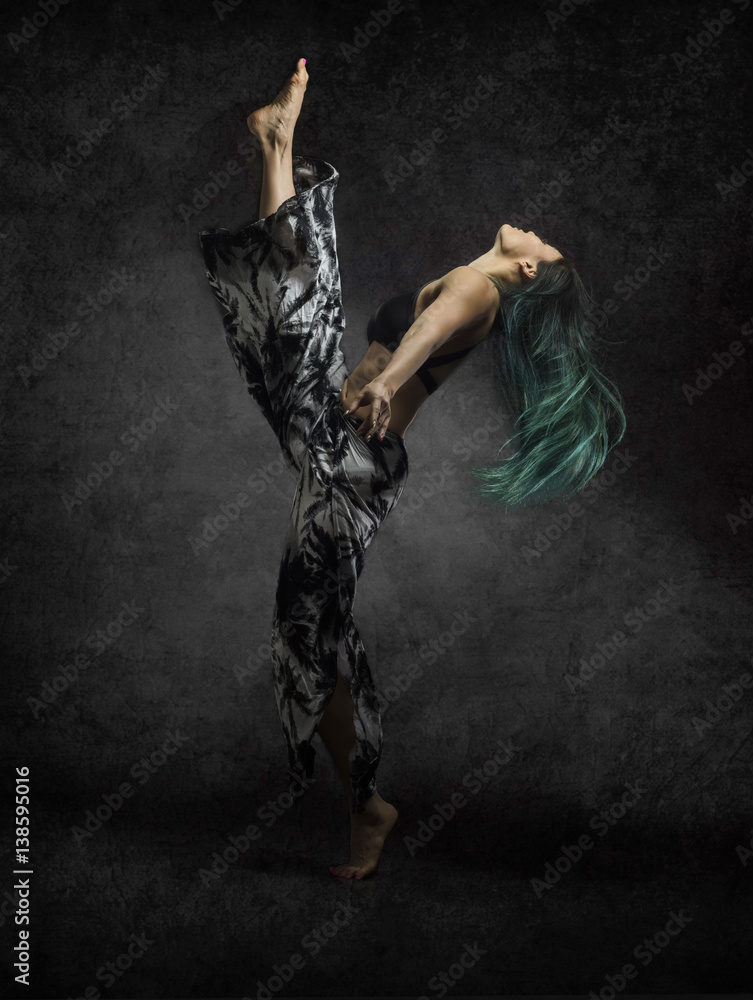 beautiful strong asian with long green hair dances with sensual dramatic graceful poses on dark textured background  