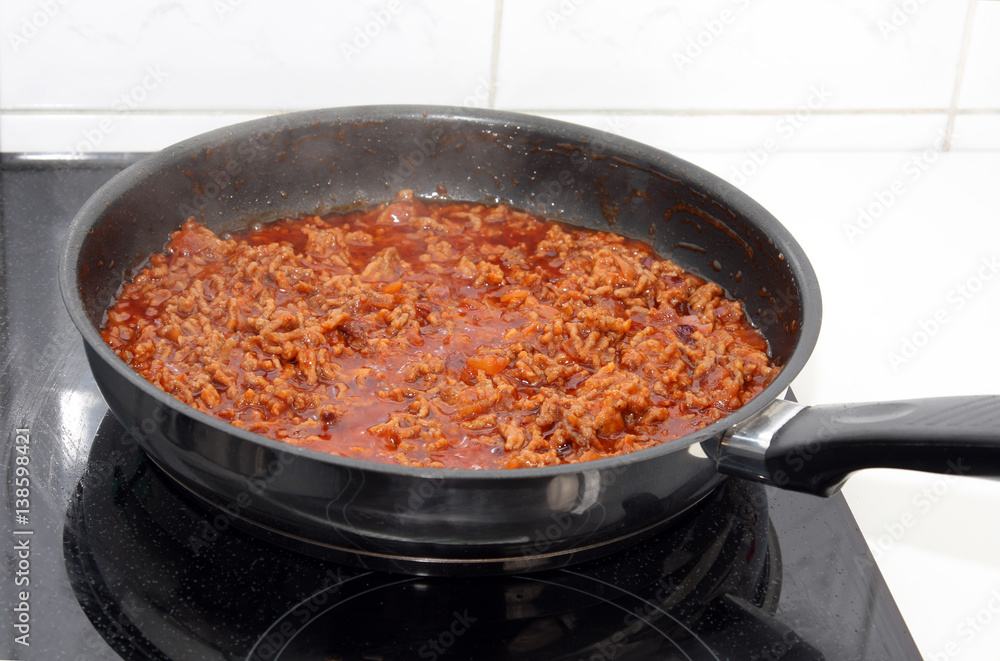 preparation sauce bolognese: mincemeat, onion and garlic in frying-pan on stove