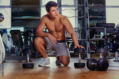 Muscular man with dumbbells gym after exercising.