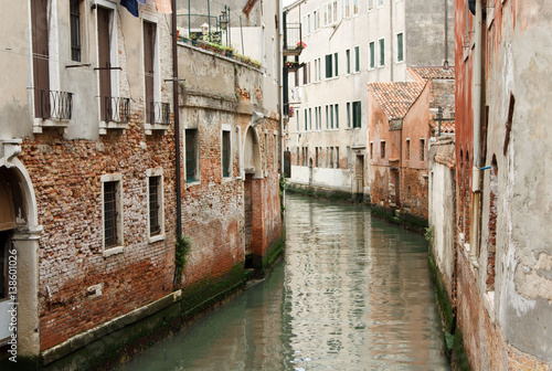 The river flows through the narrow streets of Venice between old houses in Italy © Oksana Stepova