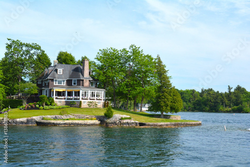 Fototapeta Island with house, cottage or villa in Thousand Islands Region in sunny summer day in Kingston, Ontario, Canada