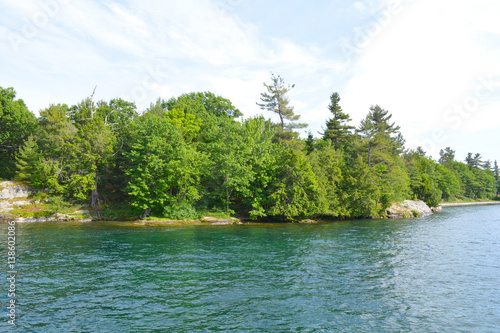 1000 Islands Region. Sunny summer day. Rocky Island on the St. Lawrence River crowned with pine trees. Kingston  Ontario  Canada. Unfiltered  natural lighting. Tourist routs.