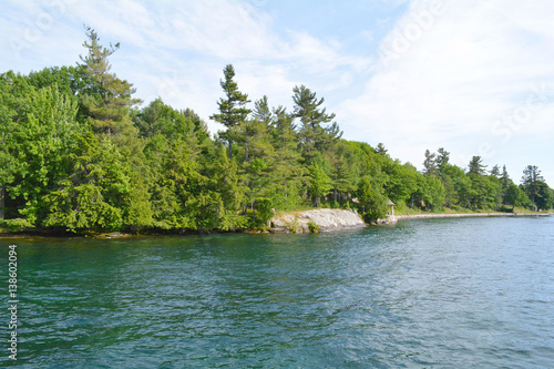 1000 Islands Region. Sunny summer day. Rocky Island on the St. Lawrence River crowned with pine trees. Kingston, Ontario, Canada. Unfiltered, natural lighting. Tourist routs. © desertsands