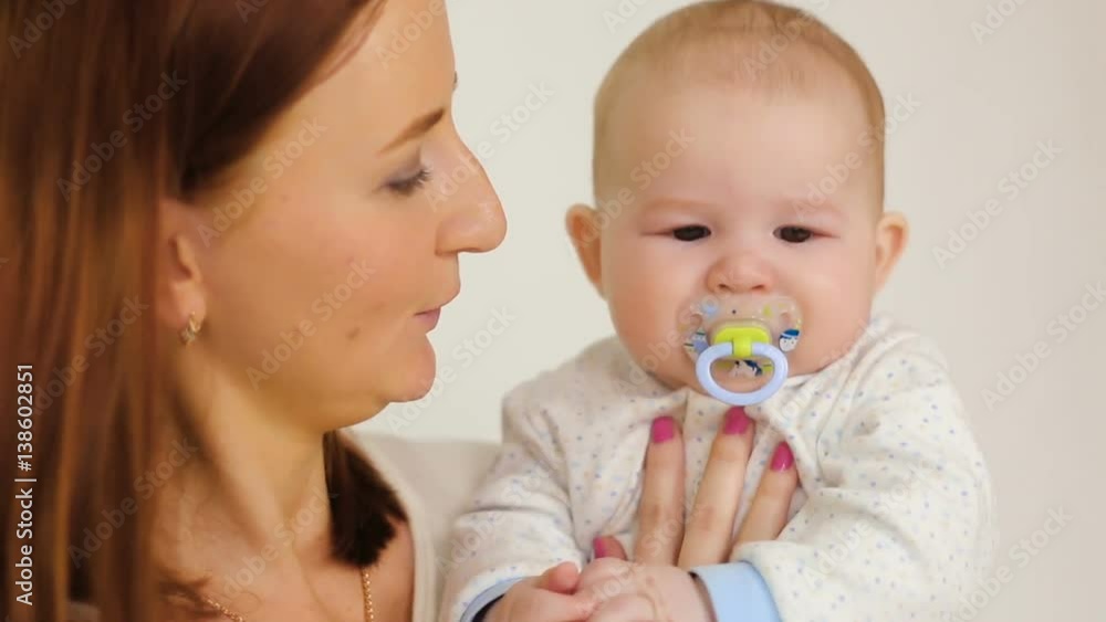 mother holding son with a pacifier on a white background mother holding son with a pacifier on a white background