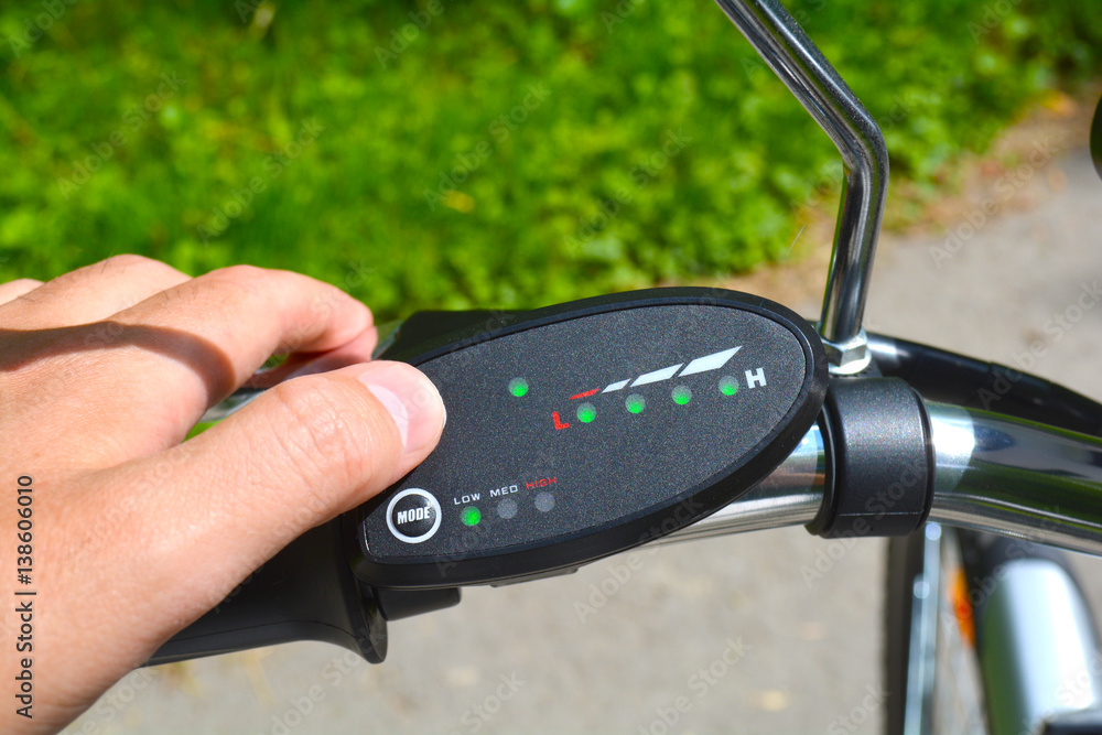 Turning on electric bike, E-bike or bicycle. Pressing a button on control board or controller to choose speed and power level. Unfiltered, with natural lighting Turning on electric bike, E-bike or bicycle. Pressing a button on control board or controller to choose speed and power level. Unfiltered, with natural lighting
