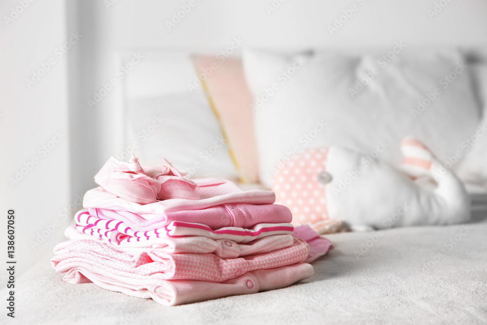 Set of baby clothes and toy on bed Set of baby clothes and toy on bed