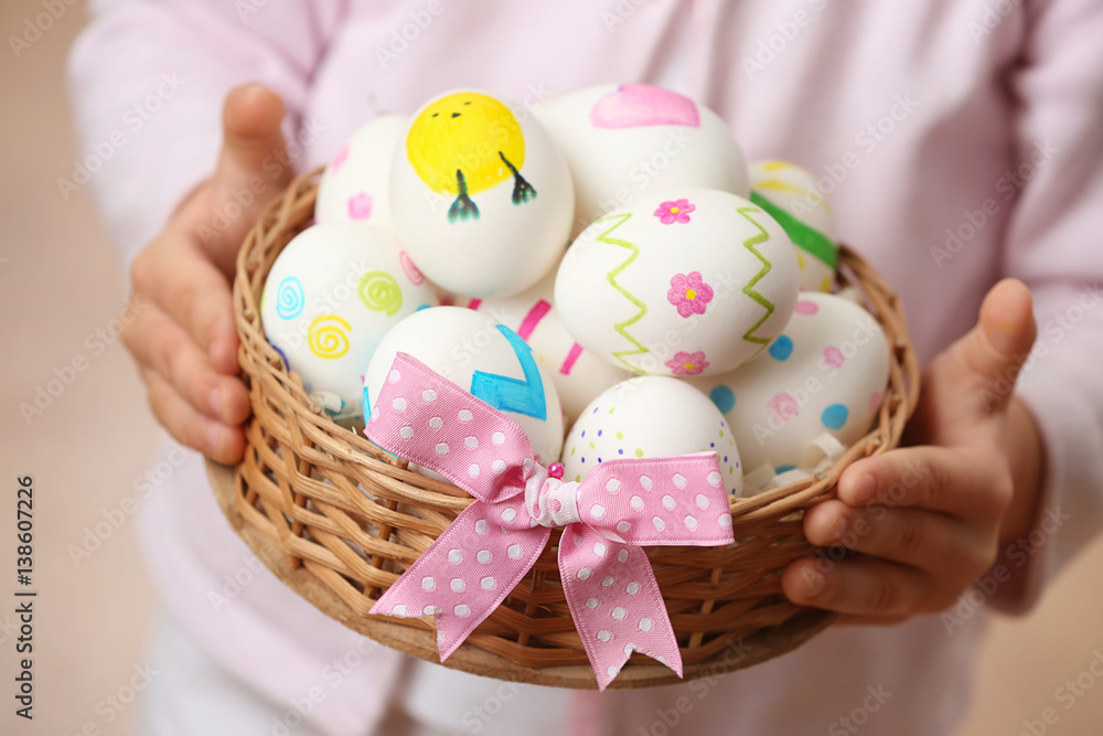 Cute child holding wicker basket with Easter eggs, closeup