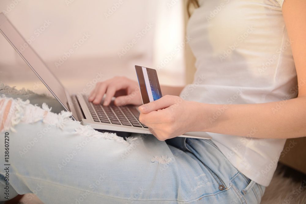 Fototapeta premium Young woman shopping online with credit card and laptop at home