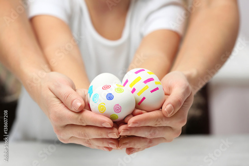 Hands of mother and child holding painted Easter eggs, closeup