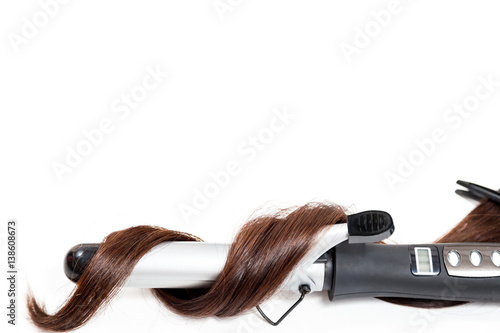 Curly dark hair with a curling iron isolated on white background