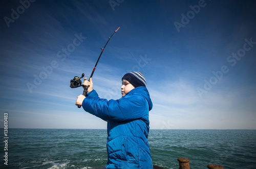 The little boy does cast a fishing rod in the sea.