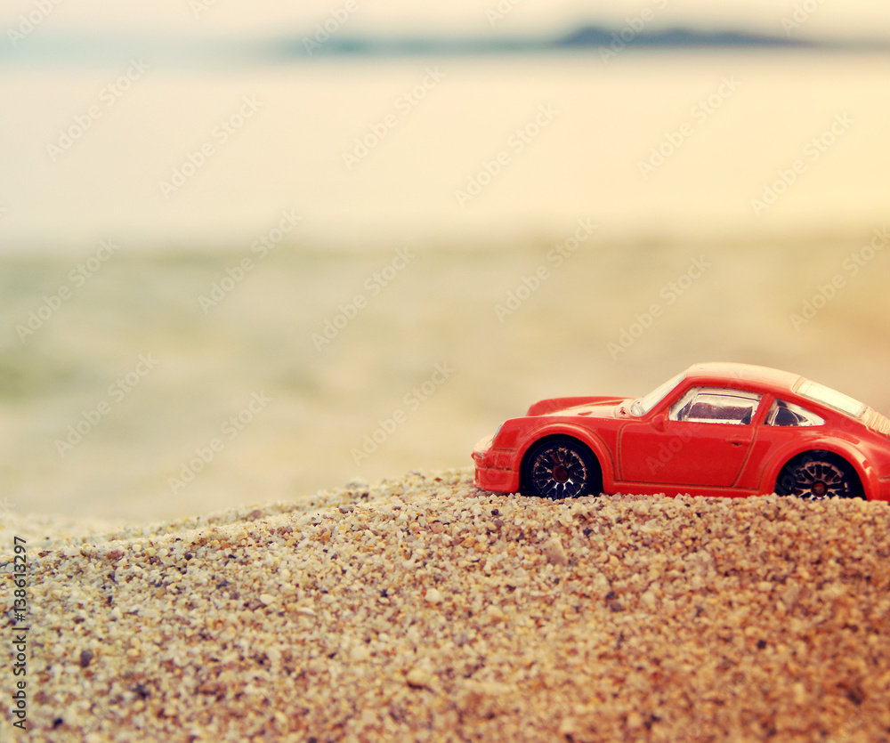 Naklejka premium Children's red machine on sea sand against the background of the sea