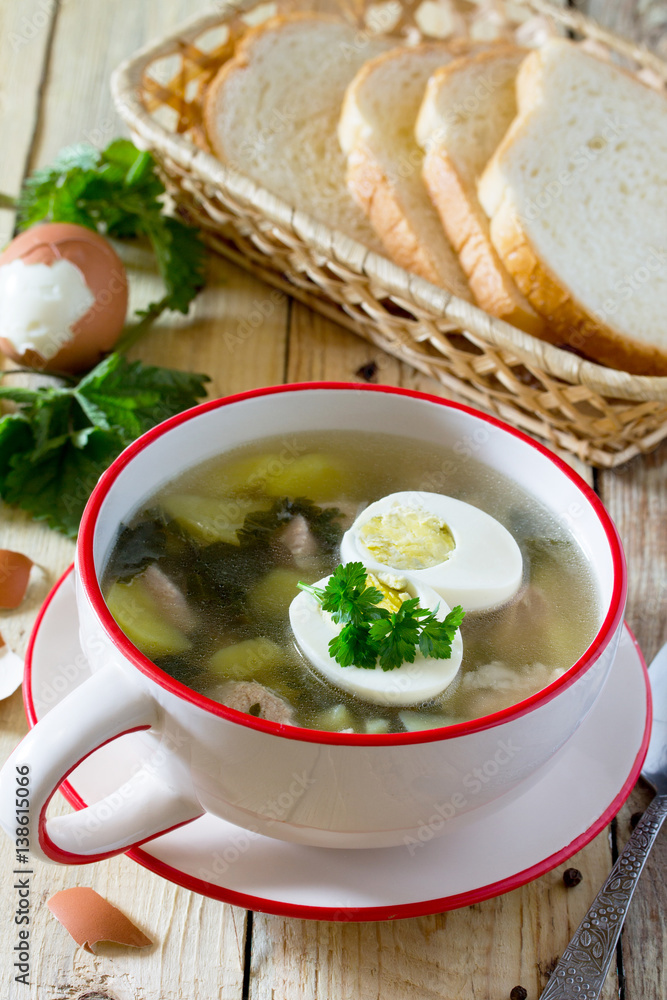 Soup with fresh nettles, egg, meat and potatoes. Fresh nettle leaf on the kitchen table a rustic background. Soup with fresh nettles, egg, meat and potatoes. Fresh nettle leaf on the kitchen table a rustic background.
