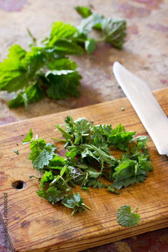 The crushed leaves brewed raw nettles on the kitchen table a rustic background. The crushed leaves brewed raw nettles on the kitchen table a rustic background.