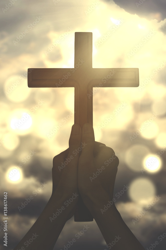 Hands hold a cross with sunbeam