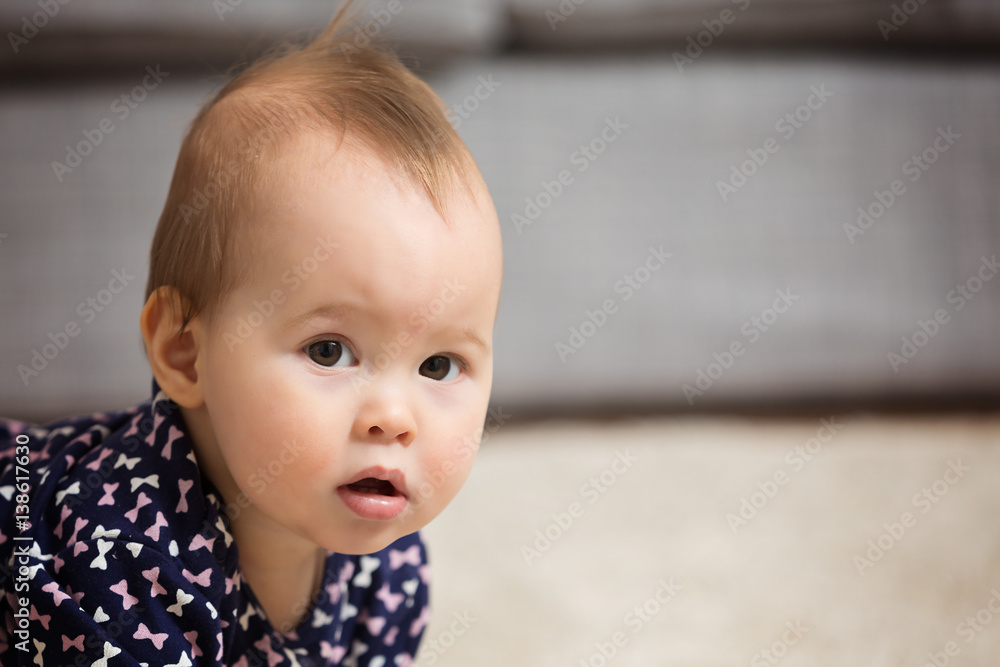 Nine months old baby girl sitting on the floor; portrait of a baby with copy space