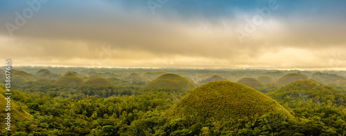 Scenic view of the UNESCO site of Chocolate Hills in Bohol, Philippines, with clouds and sun photo