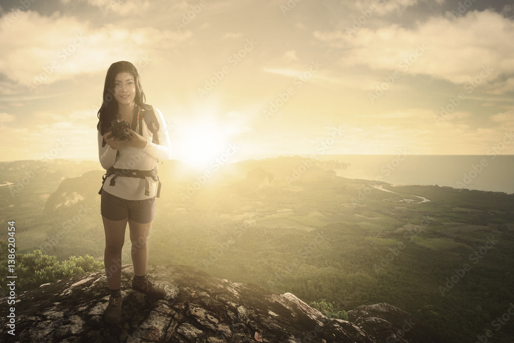Woman hiker and digital camera at sunrise
