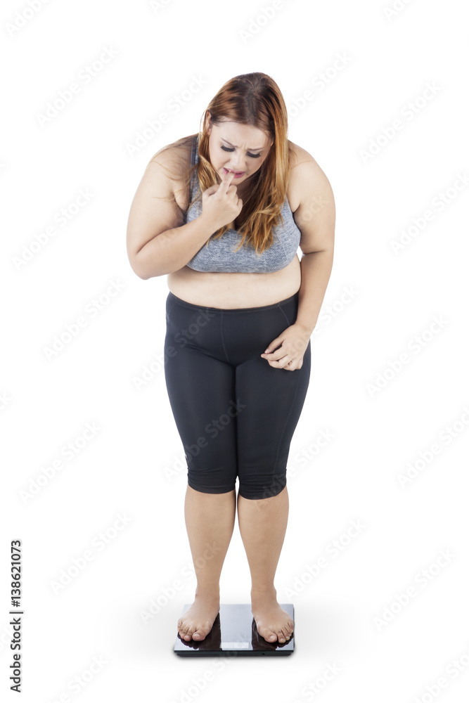 Worried obese woman on weighing scale Worried obese woman on weighing scale