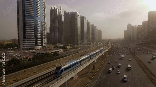 the train goes over the viaduct, along the highway among the skyscrapers in Dubai, UAE