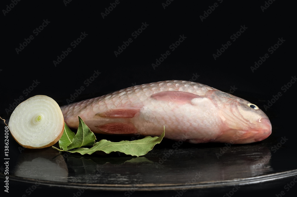Raw freshwater fish on the table and a black background.Place for text. Raw freshwater fish on the table and a black background.Place for text.