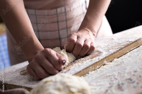Close up of female baker hands kneading dough and making bread
