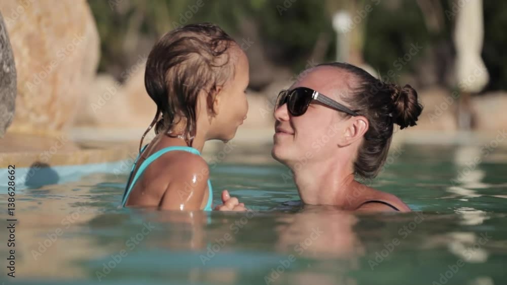 Happy pretty mother and her daughter have a fun in swimming pool Happy pretty mother and her daughter have a fun in swimming pool