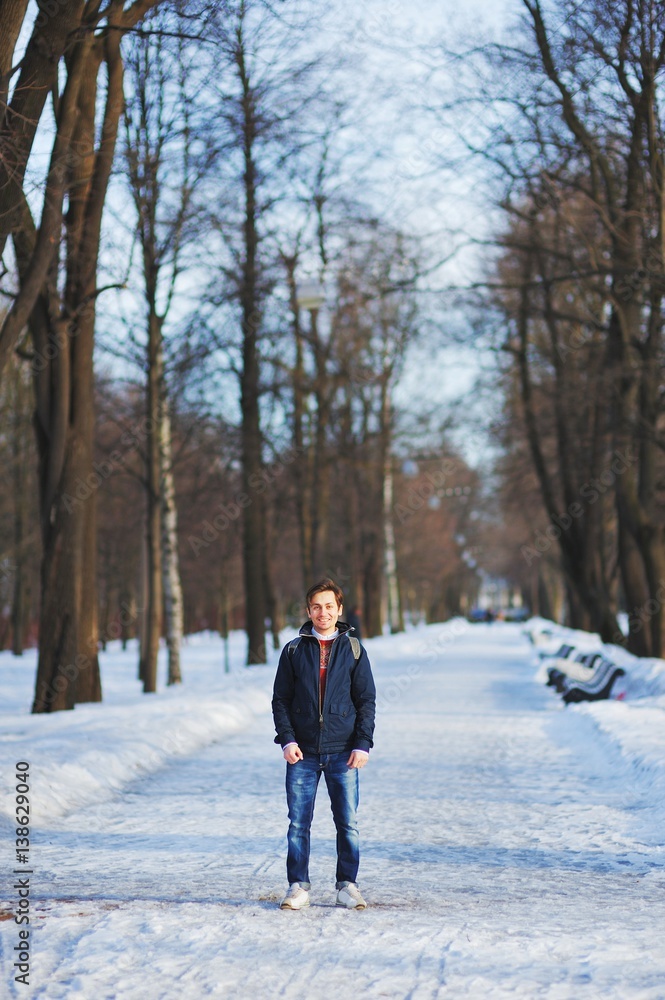 Young smiling man walks through the snowy Park on a clear winter day Young smiling man walks through the snowy Park on a clear winter day