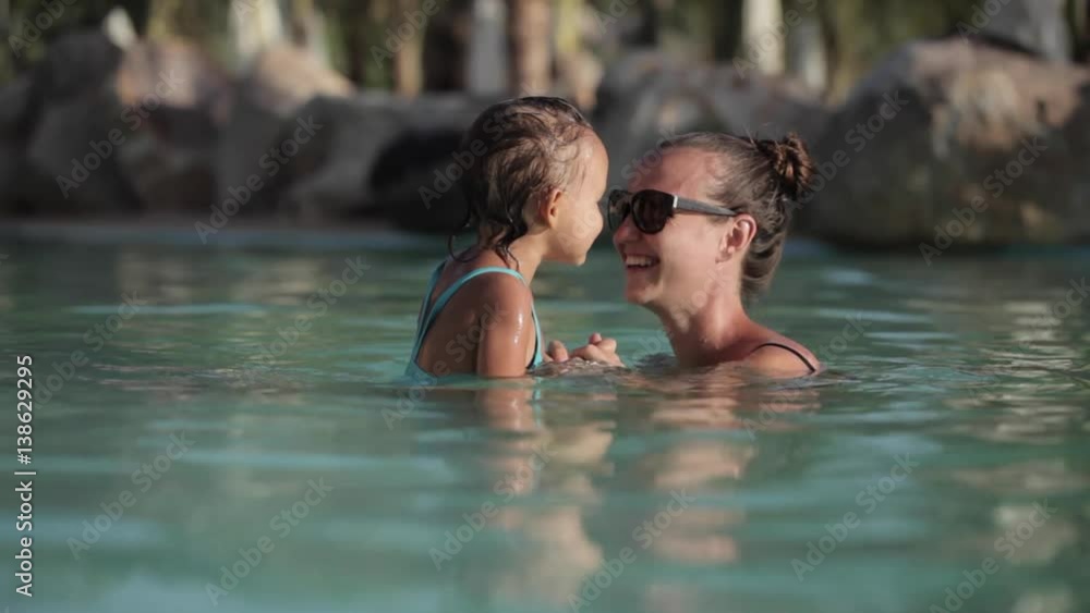 Happy pretty mother and her daughter have a fun in swimming pool Happy pretty mother and her daughter have a fun in swimming pool