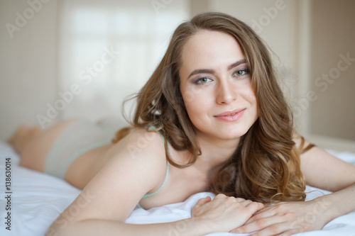 portrait of young woman in underwear lying in bed