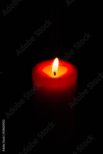 Burning red candle in the dark.