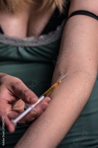 woman holding needle next to vein in arm, getting ready to shoot up, drugs, heroin