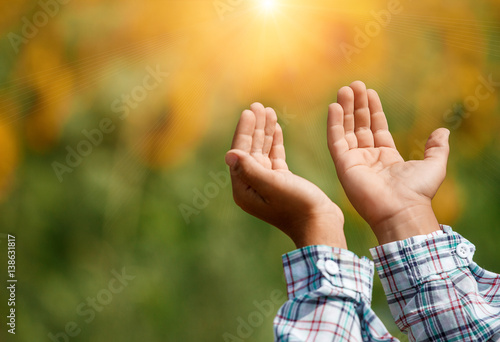 Children's open empty hands with palms up. Human hands of prayer. Sunlight in the sky
