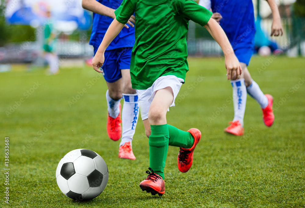 Young Boys Kids Children Playing Football Soccer Game. Running Soccer Players in Green and Blue Uniforms. Boys Kicking Soccer Ball Young Boys Kids Children Playing Football Soccer Game. Running Soccer Players in Green and Blue Uniforms. Boys Kicking Soccer Ball