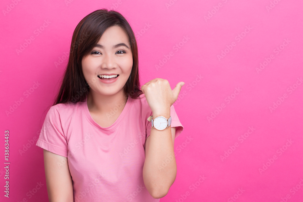 Asian woman pointing to the copy space isolated on pink background Asian woman pointing to the copy space isolated on pink background