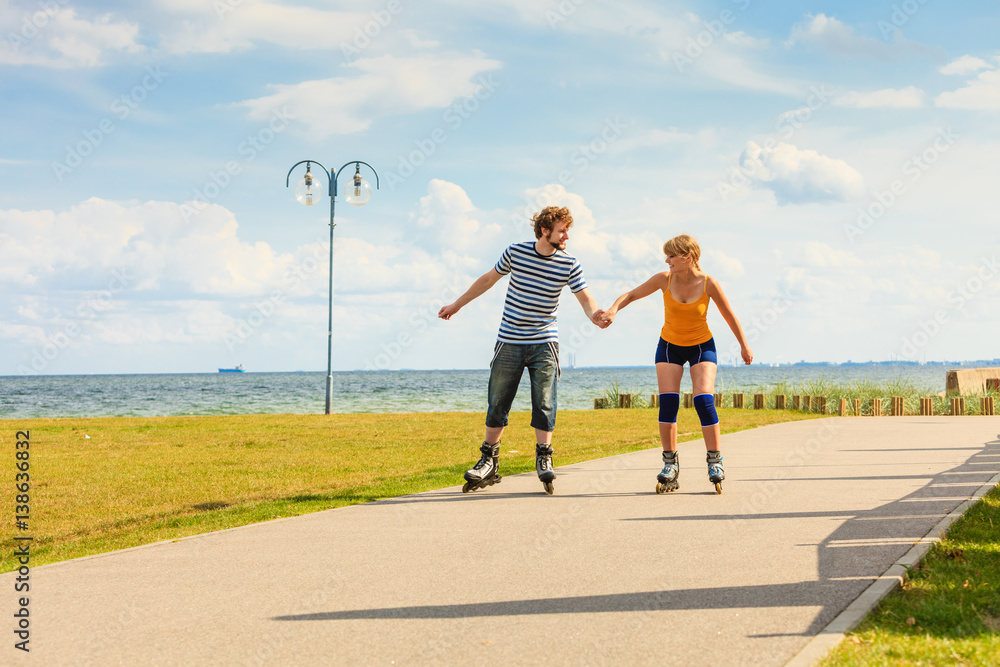 Obraz premium Young couple on roller skates riding outdoors