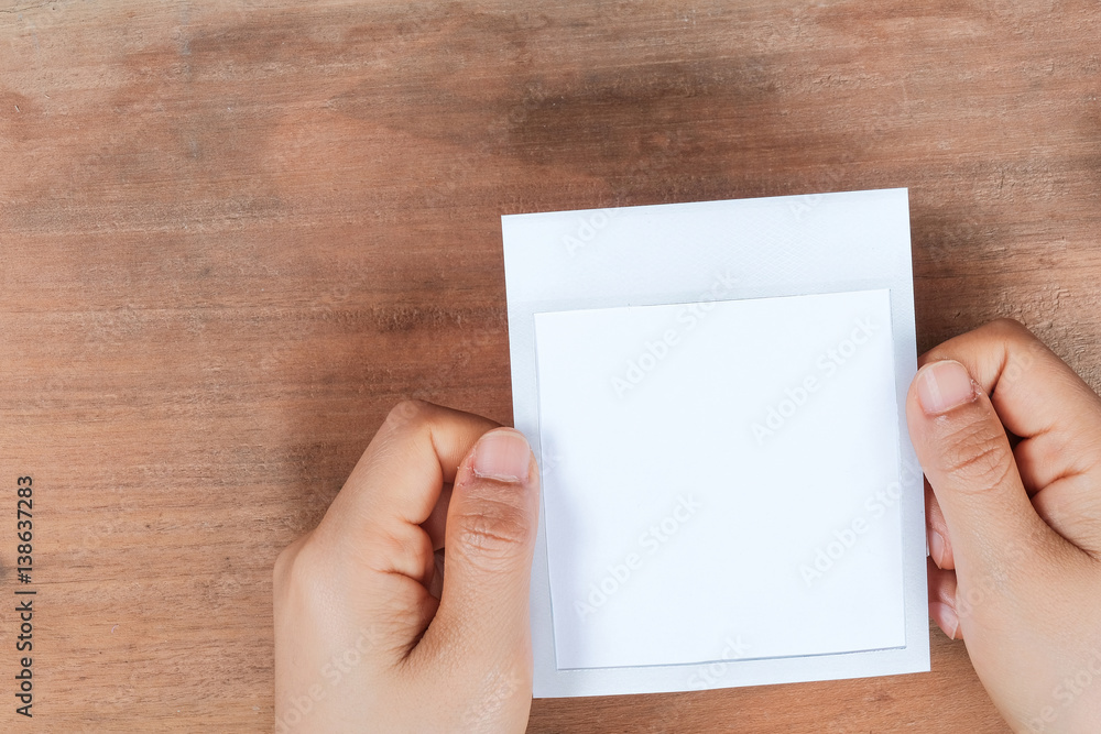 Hand holding a blank photo frame in front of wooden background. Hand holding a blank photo frame in front of wooden background.