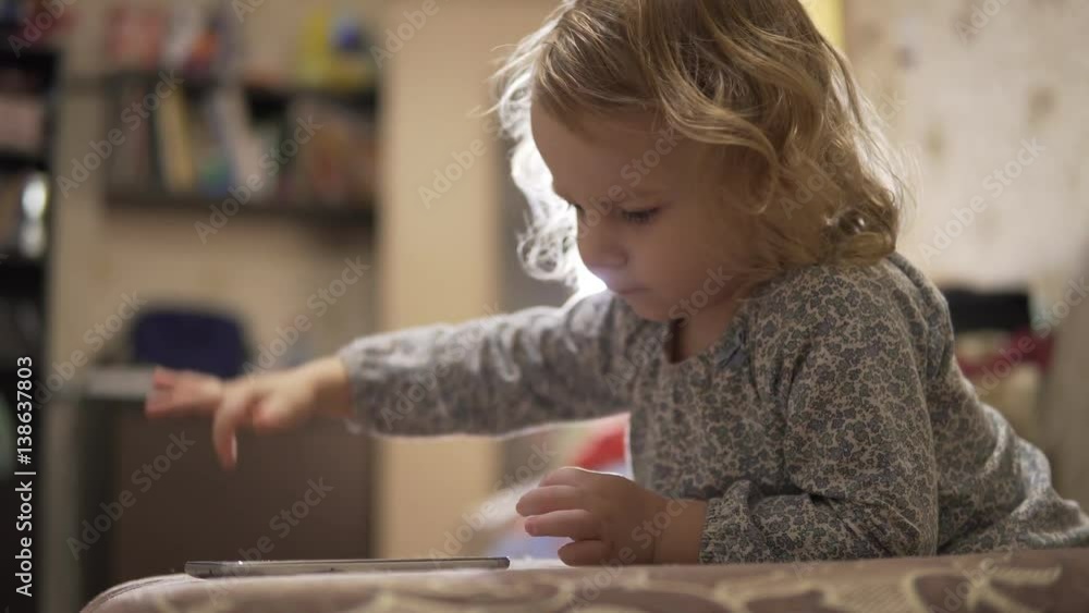 Little girl playing with toys and watching the tablet Little girl playing with toys and watching the tablet