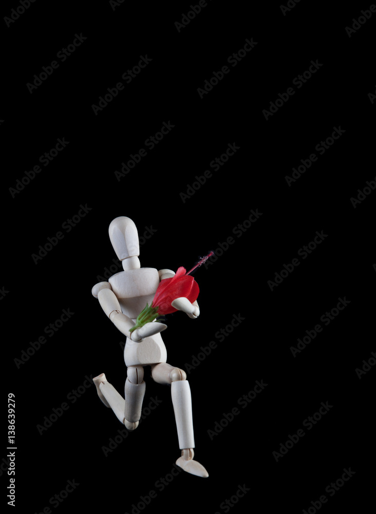 Wooden figurine kneeling with flower on black background with copy space. Wedding, engagement, valentines concept Wooden figurine kneeling with flower on black background with copy space. Wedding, engagement, valentines concept