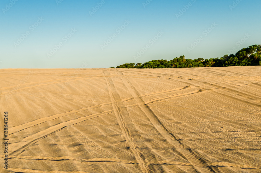 White and yellow sand in the desert with quad bike and car jeep tracks