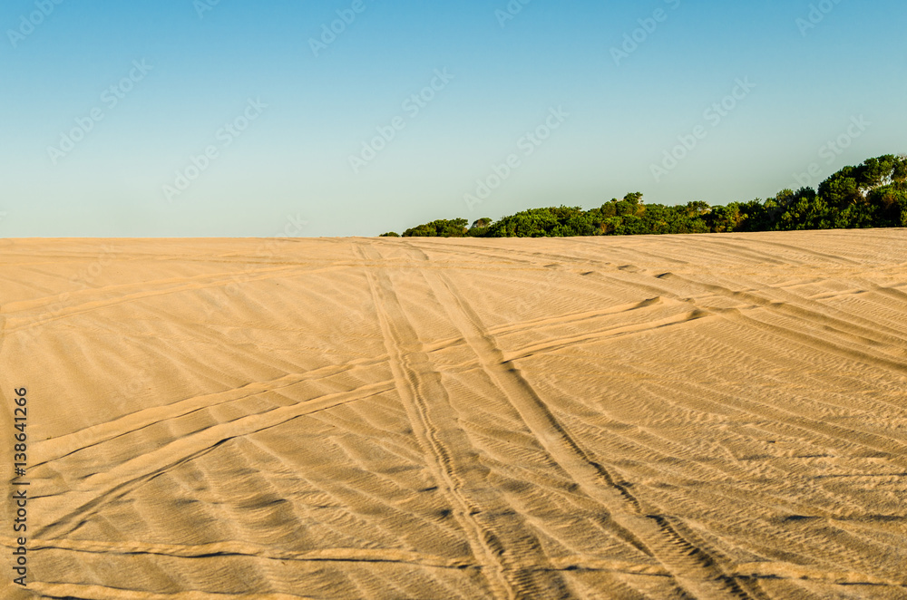 White and yellow sand in the desert with quad bike and car jeep tracks White and yellow sand in the desert with quad bike and car jeep tracks