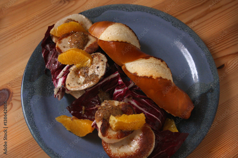 Laugenstange mit gebratener Gelbwurst, Orangen und Radicchio Stock-Foto ...