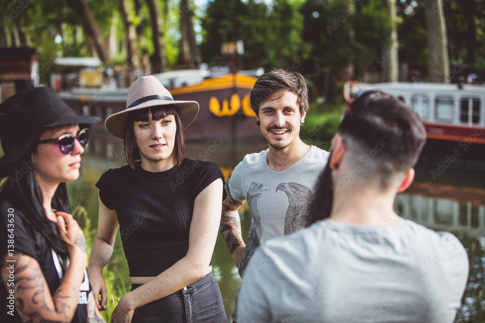 Fototapeta premium Groupe de jeunes Hipster en pleine discussion sur les berges de la Garonne, des péniches en arrière plan