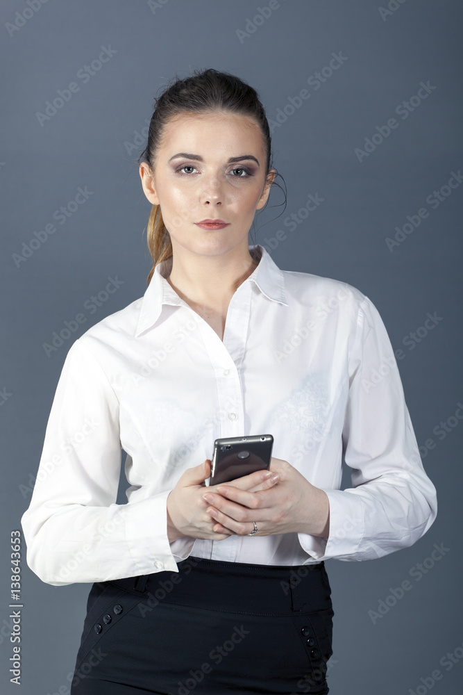 Young attractive serios business woman with smartphone looks directly. Portrait
Young attractive serios business woman with smartphone looks directly. Portrait